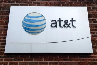 A white sign with the AT&T name and logo on a brick background