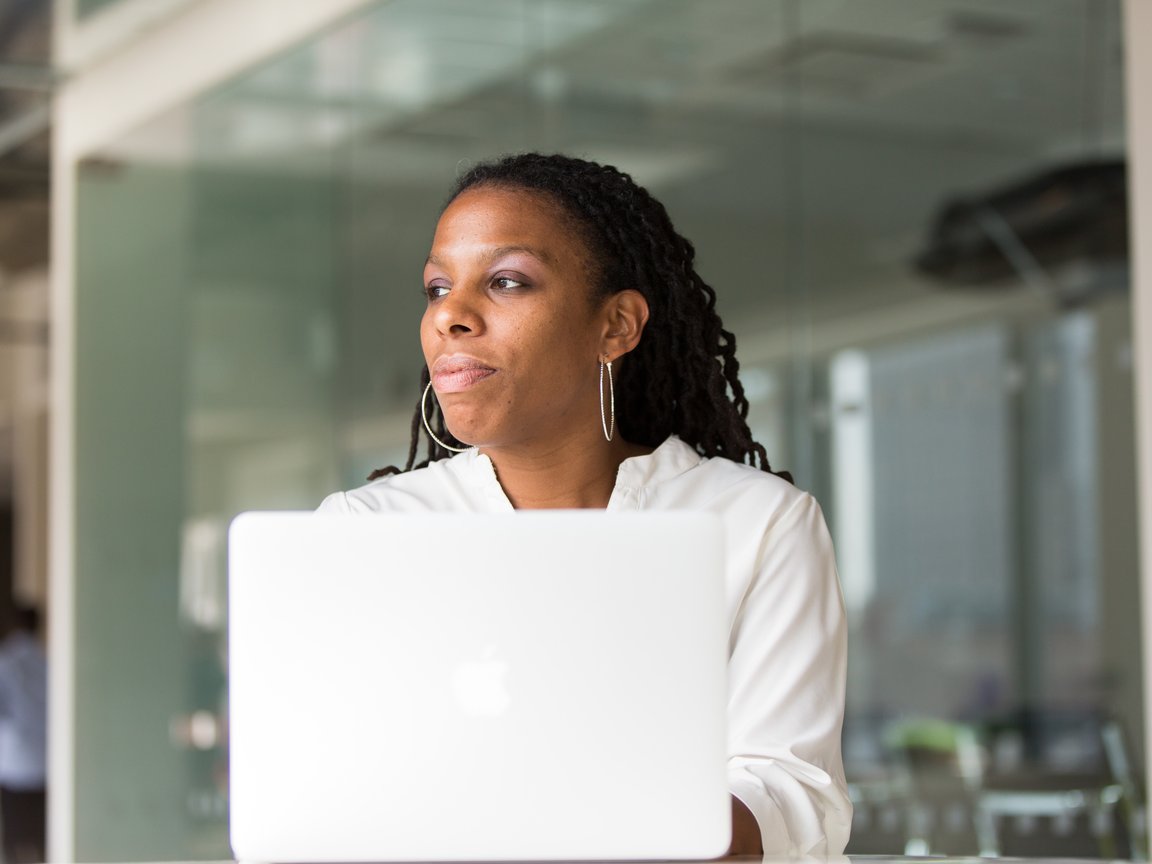Header image of a woman sitting in front of her computer in an office.
