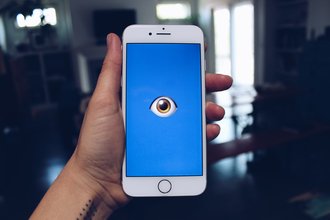 Stock photo of a phone staring back with a single eye emoji on its display