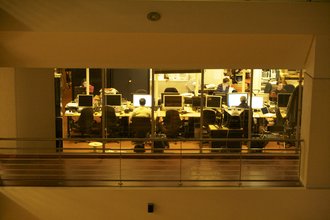 A photo peering into a window of the French newsroom, Le Point, where reporters are working at their desks.