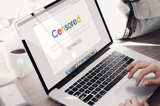 A laptop open to a web page with the word "Censored" in colored letters that evoke Google's logo