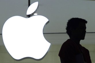 A person stands near the Apple logo at the company's store in Grand Central Terminal, in New York on in December 2011