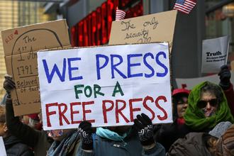 A group of protesters hold signs in solidarity with the press in February 2017; one says, “We press for a free press”