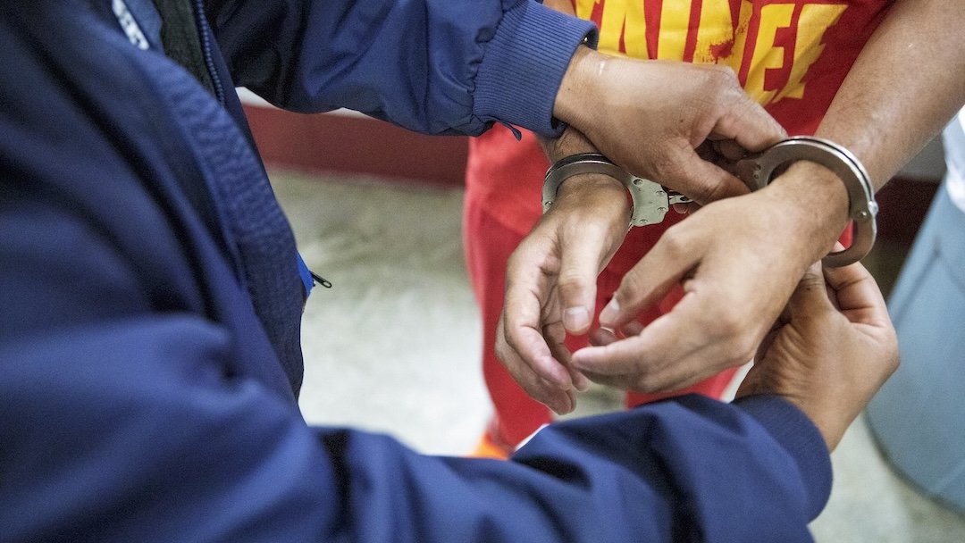 a close up photo of a pair of hands being handcuffed by another pear of hands.