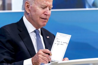 President Joe Biden holds a card handed to him by an aide that reads "Sir, there is something on your chin" in the Eisenhower Executive Office Building on the White House Campus in Washington, July 30, 2021