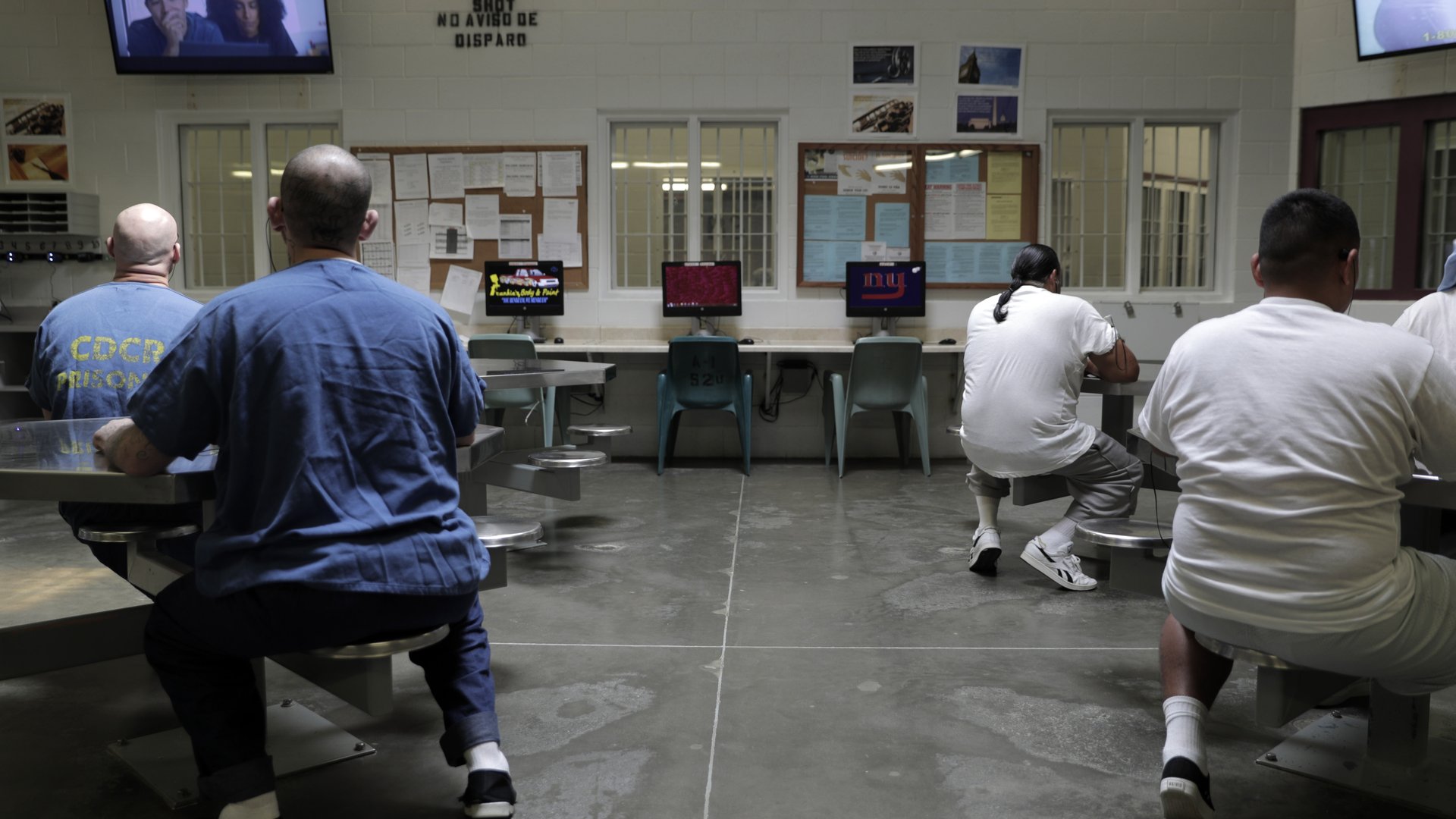 Four people sitting and watching television in a prison.