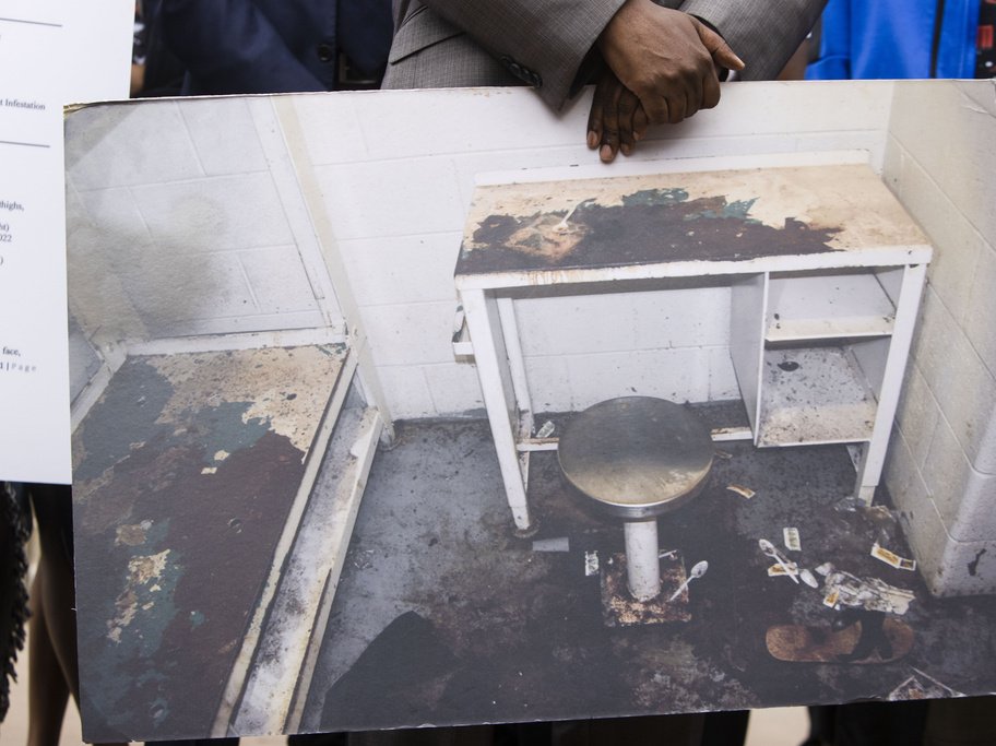 An attorney holds a photo of the bedbug-invested Georgia jail cell where Lashawn Thompson died in 2022.