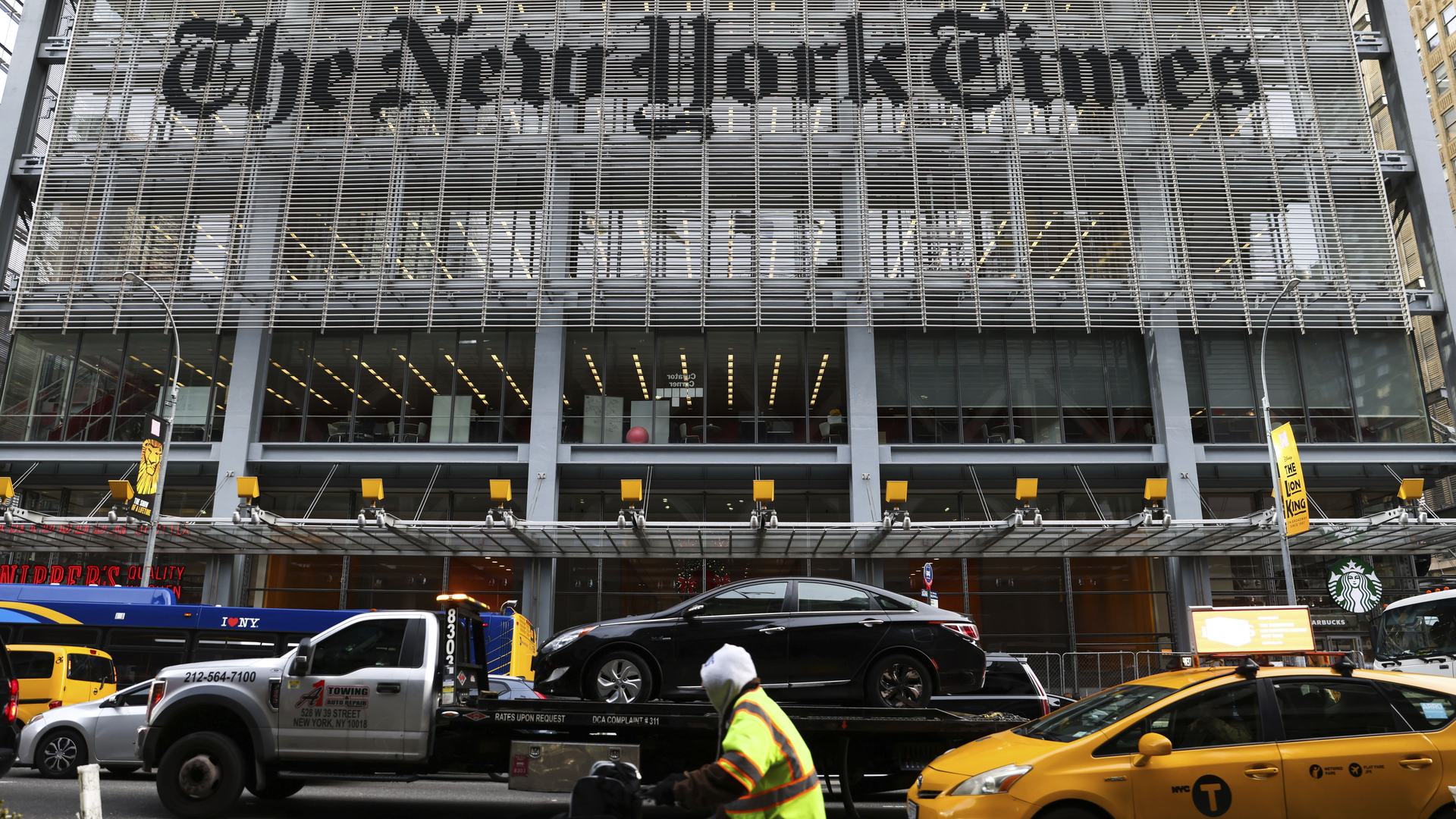 The entrance to the New York Times headquarters in New York City, with a stream of traffic passing in front of it.