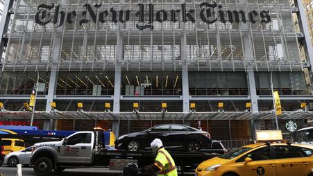 The entrance to the New York Times headquarters in New York City, with a stream of traffic passing in front of it.