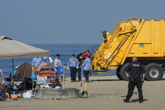 Los Angeles police and county workers remove a homeless encampment at a California state beach in August.