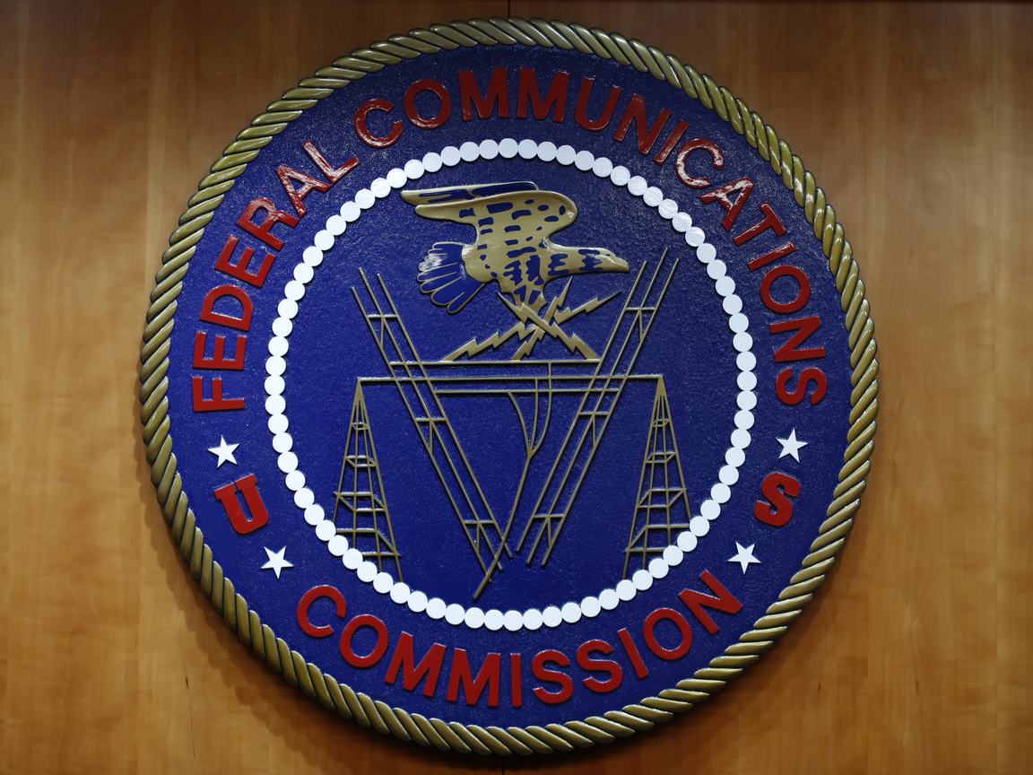 Image of the FCC seal: a blue emblem with the words “Federal Communications Commission” in red with an eagle in the center flying over images of communications technology.