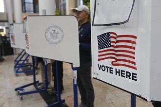 A file photo that features white polling booths that have an American flag printed on them with the text "vote here"