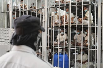 A photograph of a prison in El Salvador that shows prisoners stacked upon one another behind bars.