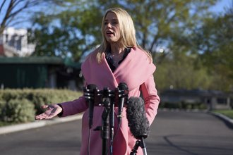 Attorney General Pam Bondi talking to reporters in a pink coat.