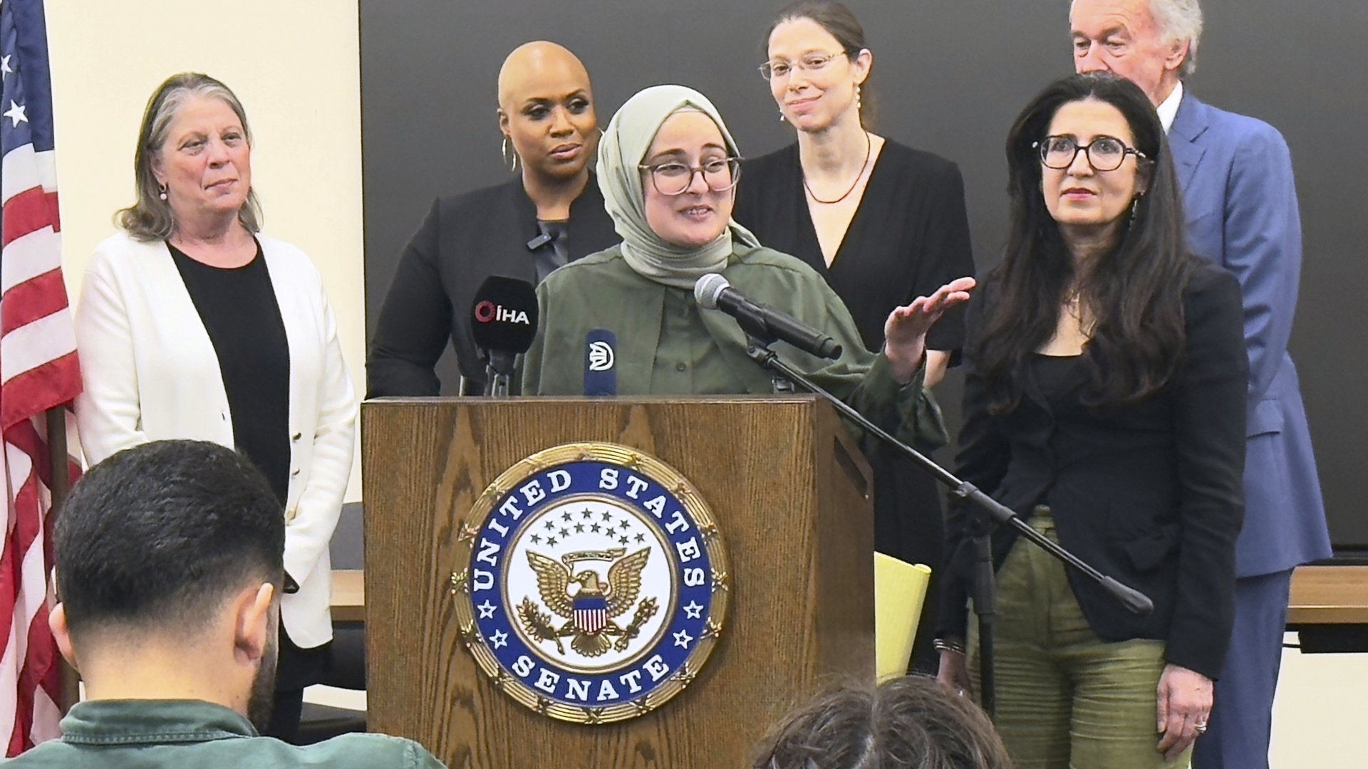 A photo featuring Tufts University student Rumeysa Öztürk in the center surrounded by reporters at a press conference.