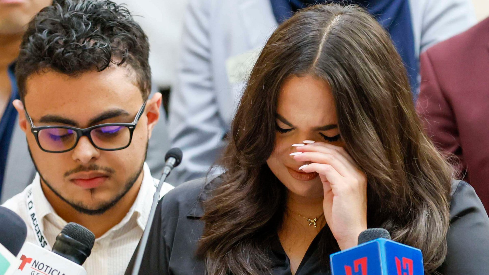 A woman cries in front of a microphone at a press conference.