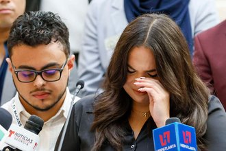 A woman cries in front of a microphone at a press conference.