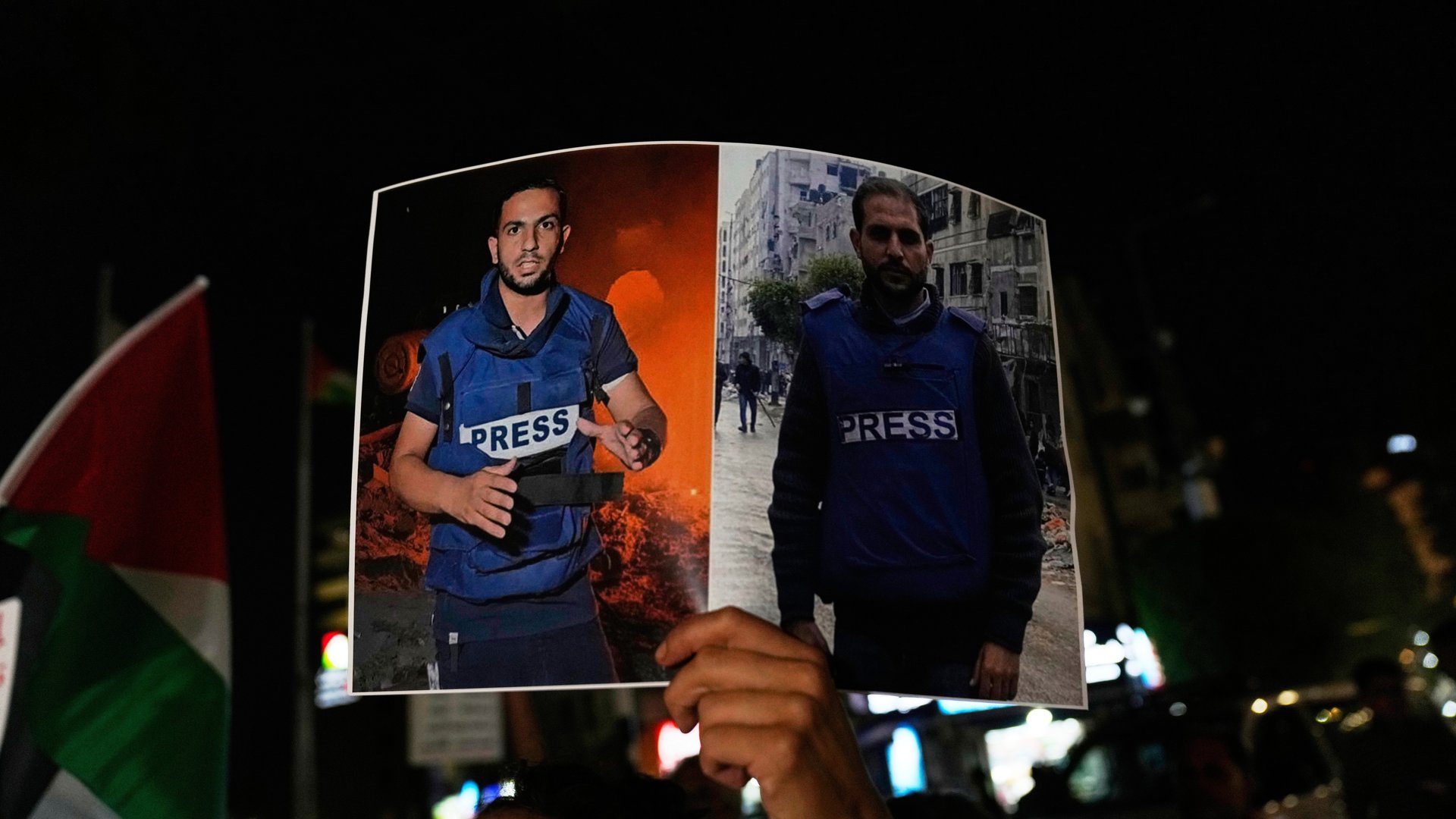 A photo of a protester's hand holding a placard on which two Palestinian journalists are pictured.