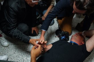 Bystanders assist journalist L. Vural Elibol, chief videographer for Turkey’s Anadolu Agency, as he lies on the floor after being shoved by federal officers while covering detentions in New York City’s immigration court on Sept. 30, 2025.