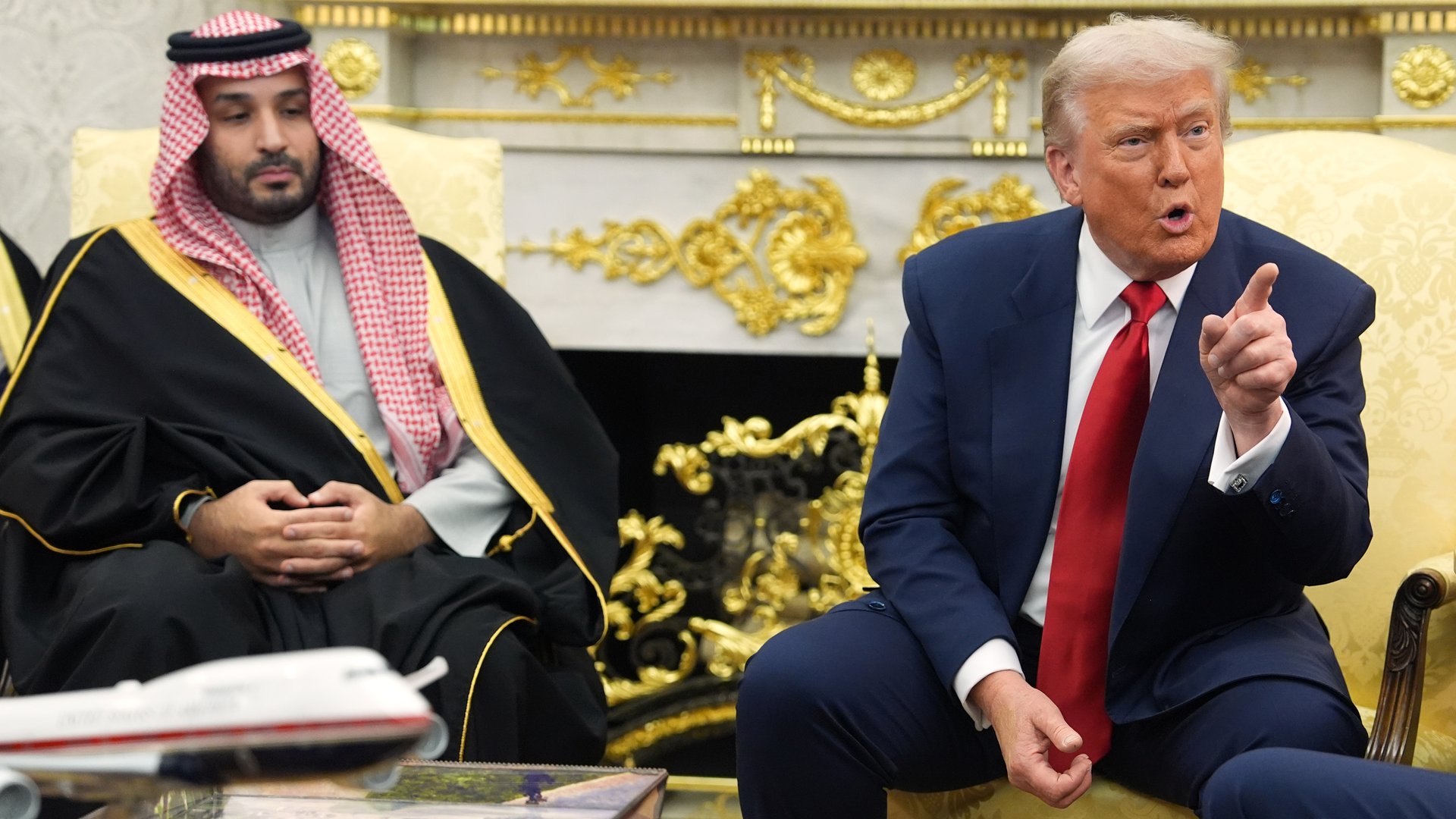 The Saudi Crown Prince sits on the left while Donald Trump sits on the right, pointing with his index finger and emoting to the audience.