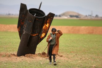 A boy walks away from an unexploded Iranian projectile that landed in Syria.