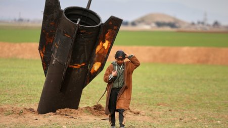 A boy walks away from an unexploded Iranian projectile that landed in Syria.