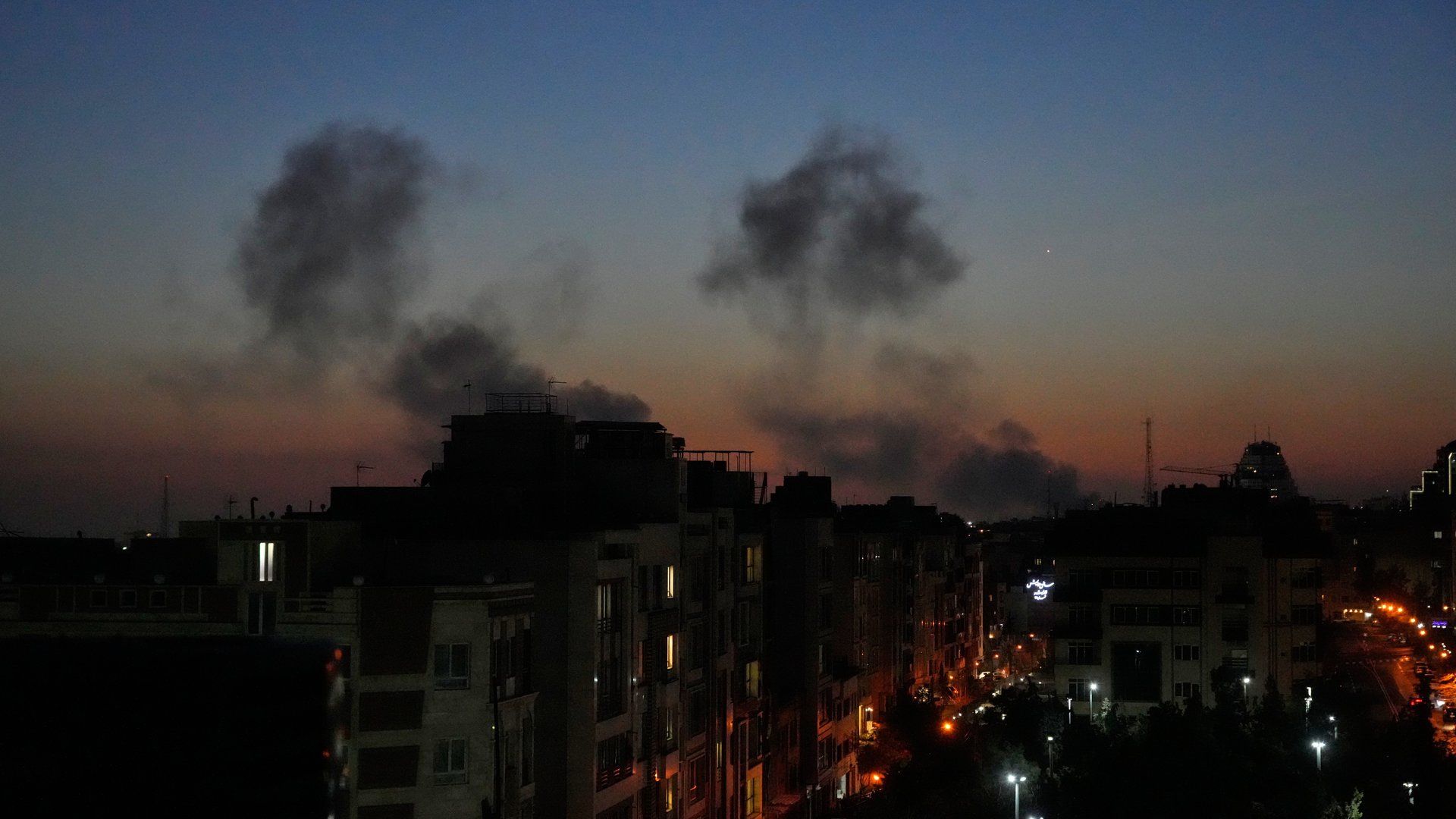 Plumes of smoke rise into the night sky over buildings in Tehran, Iran, as strikes hit the city during the U.S.–Israeli military campaign on March 6, 2026