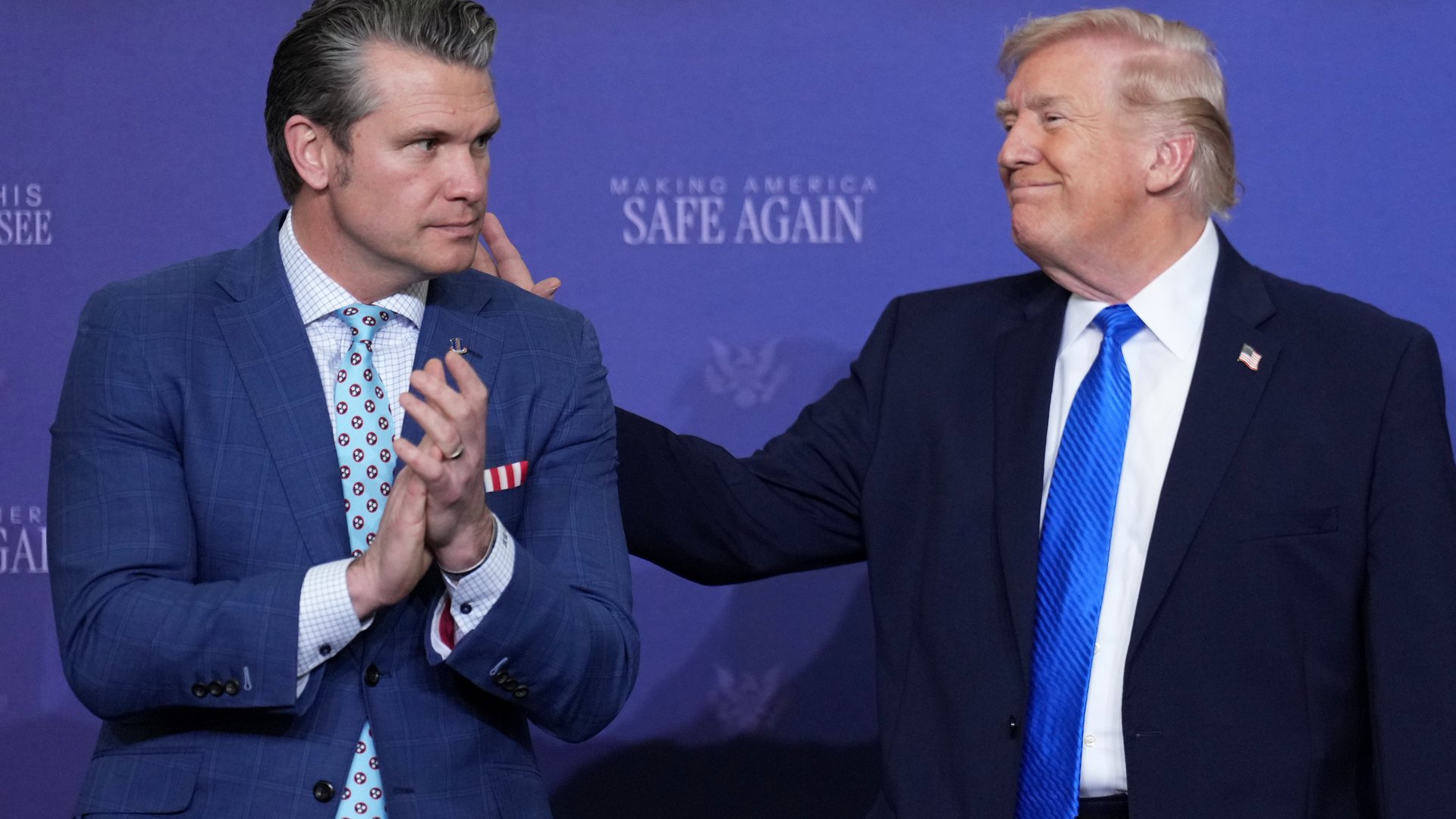 President Donald Trump patting Defense Secretary Pete Hegseth on the back