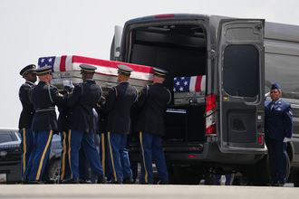 A group of soldiers places a case containing the remains of a killed soldier, draped with an American flag, into a black transfer vehicle on July 22, 2026 at Dover Air Force Base in Delaware.