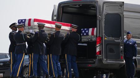 A group of soldiers places a case containing the remains of a killed soldier, draped with an American flag, into a black transfer vehicle on July 22, 2026 at Dover Air Force Base in Delaware.