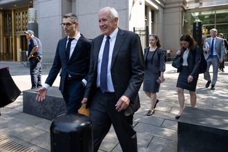 Two men wearing suits walk outside a courthouse.