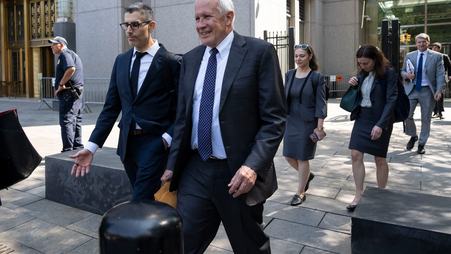 Two men wearing suits walk outside a courthouse.