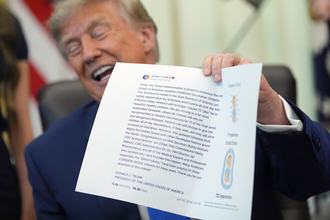 President Donald Trump holds up a piece of paper with one of his Truth Social posts on it in the Oval Office on Aug. 10, 2026.