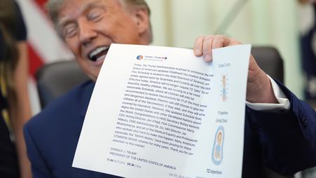 President Donald Trump holds up a piece of paper with one of his Truth Social posts on it in the Oval Office on Aug. 10, 2026.