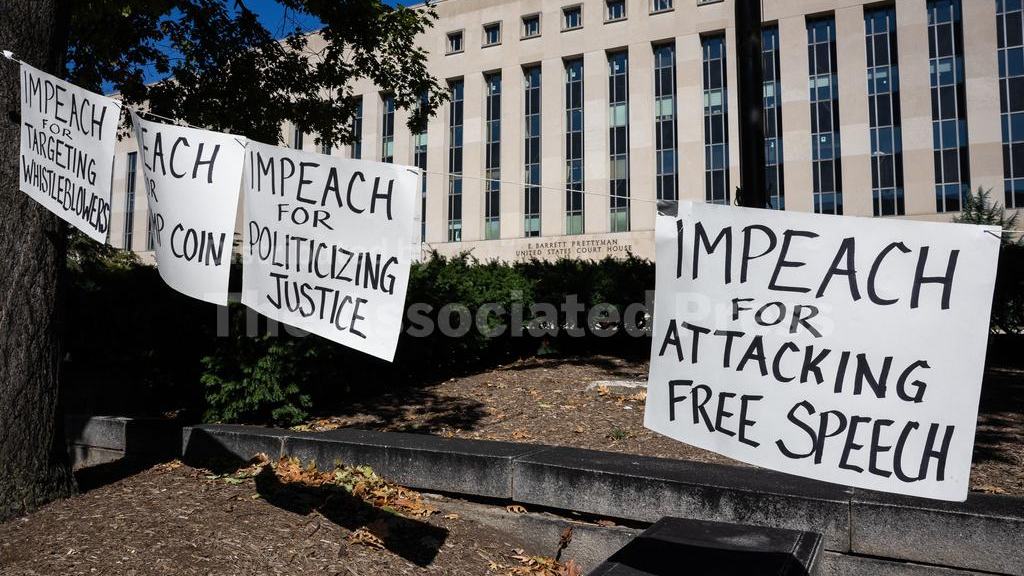 Various signs, including one that says "IMPEACH FOR ATTACKING FREE SPEECH" hang outside the E. Barrett Prettyman U.S. Courthouse during a hearing on Cable News Network, Inc. et al v. Trump in Washington, D.C., on October 8, 2026.