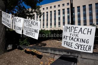 Various signs, including one that says "IMPEACH FOR ATTACKING FREE SPEECH" hang outside the E. Barrett Prettyman U.S. Courthouse during a hearing on Cable News Network, Inc. et al v. Trump in Washington, D.C., on October 8, 2026.