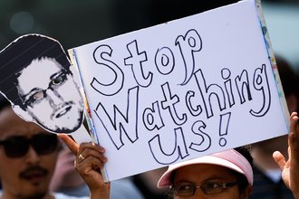 Protestor holding a sign and image of Edward Snowden