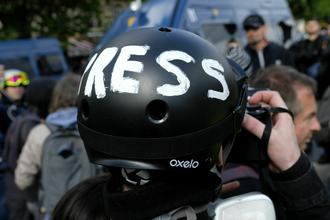 A person, seen from behind with a close-up on their head, takes a picture while wearing a black helmet with the word PRESS written in white across it.