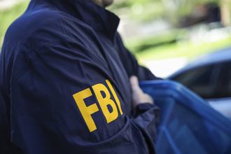 An FBI agent carrying a box of seized items