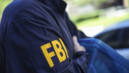 An FBI agent carrying a box of seized items