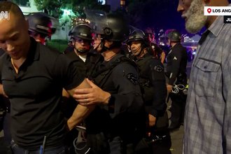 CNN correspondent Jason Carroll, far left, was detained and escorted out of a protest zone by police officers while documenting anti-deportation demonstrations in Los Angeles, California, on June 9, 2025.