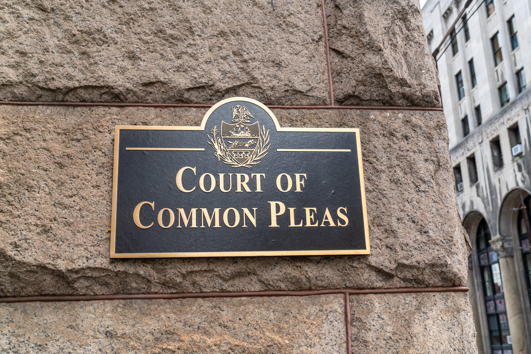 A black sign on a brown brick building reads "Court of Common Pleas"