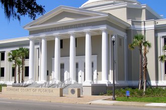 A white domed building with six columns and a concrete sign reading "Supreme Court of Florida"