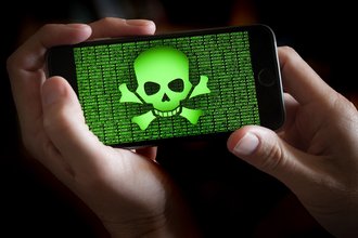 A person holds a phone displaying a green skull and crossbones and strings of numbers.