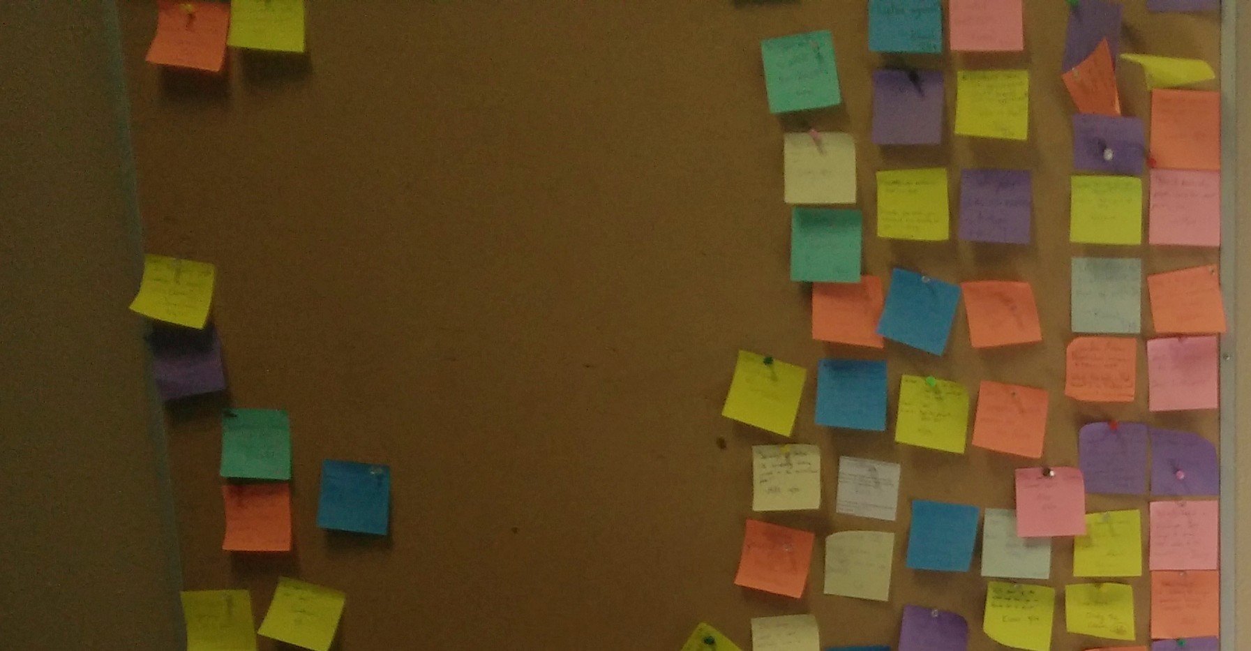 Photo of a cork board pinned with dozens of post-it notes from the student newsroom.