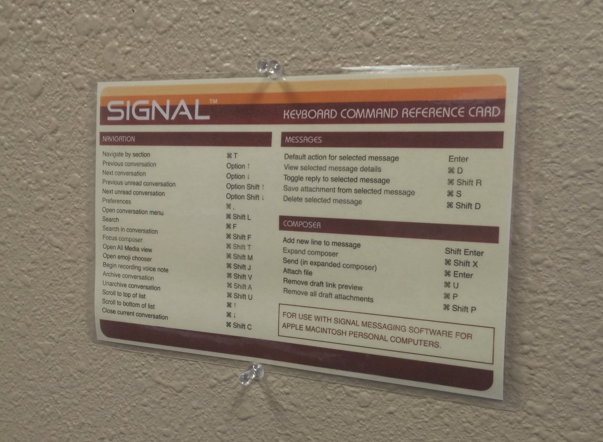 A Signal "reference card" with shortcut commands, pinned to the wall.