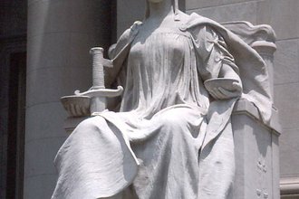Statute of Lady Justice, seated and wearing a blindfold