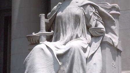 Statute of Lady Justice, seated and wearing a blindfold
