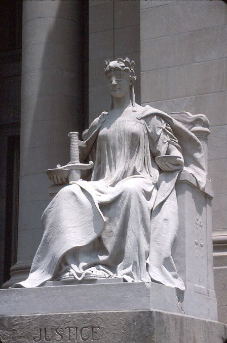 Statute of Lady Justice, seated and wearing a blindfold