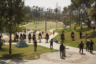 MacArthur Park during the daytime, with numerous people in law enforcement uniforms, some on horseback.